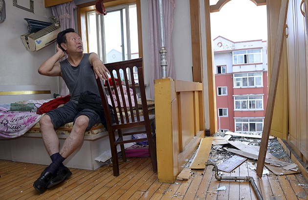 ساکن طبقۀ ششم آپارتمانی ۱۳سال‌ساخت در شنیانگ درحال نگاه‌کردن به خرابی ساختمان بعد از فروریختن بالکن. عکس: رویترز.