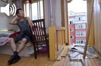 ساکن طبقۀ ششم آپارتمانی ۱۳سال‌ساخت در شنیانگ درحال نگاه‌کردن به خرابی ساختمان بعد از فروریختن بالکن. عکس: رویترز.